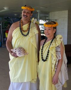 man with conch and woman with lei and flower head garland