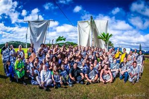 large group of people outside in front of sailing canoe